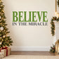 Printed wall decal text: green 'BELIEVE' and white 'IN THE MIRACLE'.