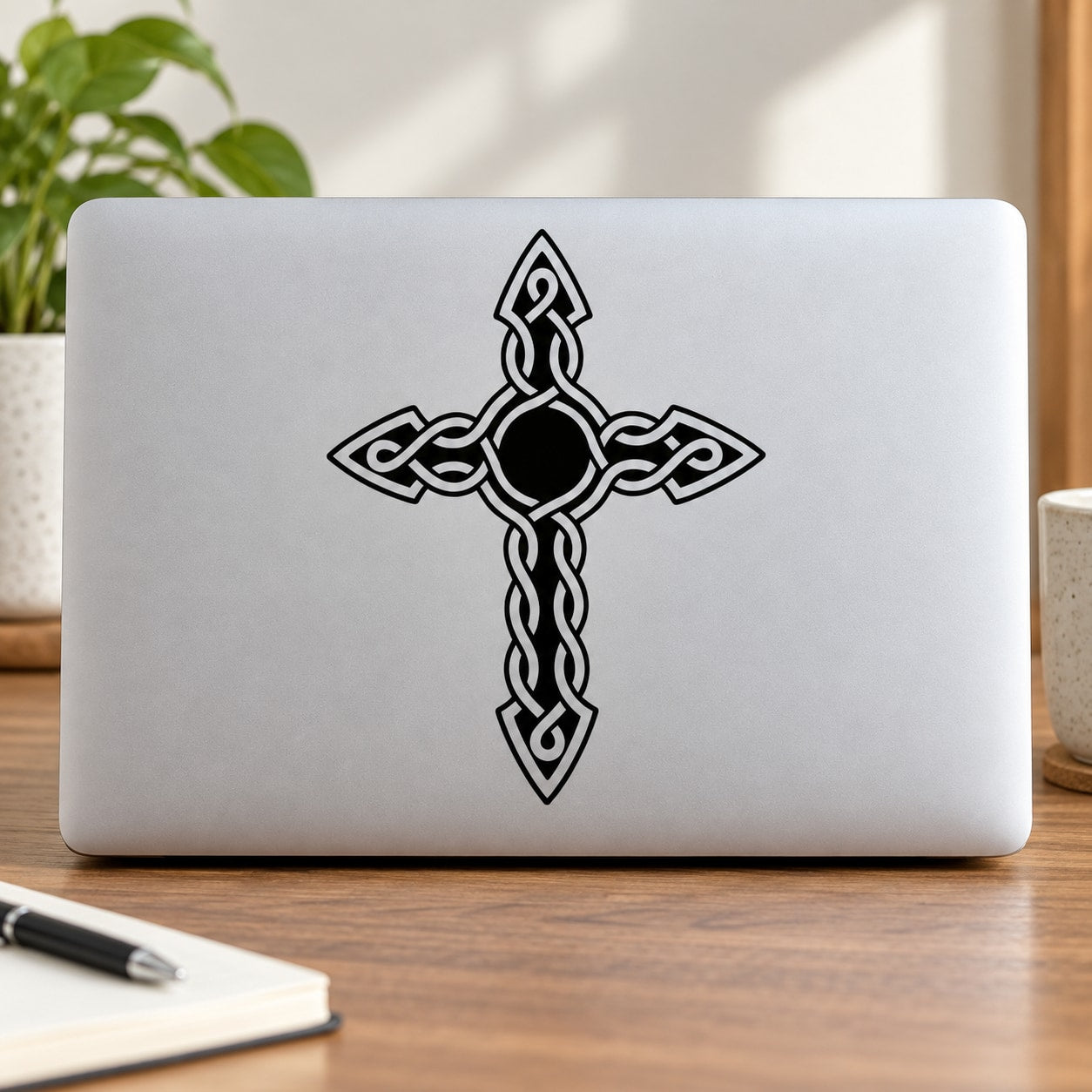 Black Celtic knot cross decal with interwoven ribbon design on a light surface
