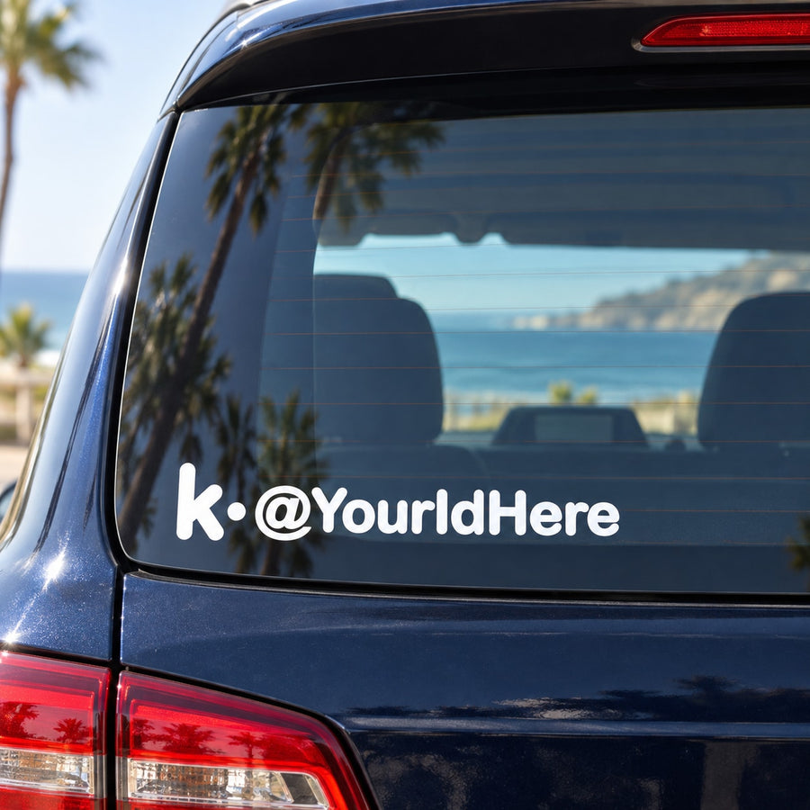 White die-cut decal with 'k.@YourIdHere' text on car rear window