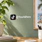 Die-cut TikTok decal with logo and @YourIdHere handle on a green wall