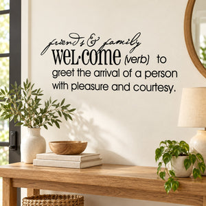 Black wall decal text: 'Friends & family welcome' with 'Welcome (verb)' definition