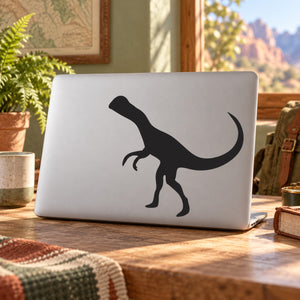 Dinosaur decal of a black Dilophosaurus head and tail on a white laptop