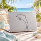 Dolphin line-art decal sticker on a light-colored laptop cover