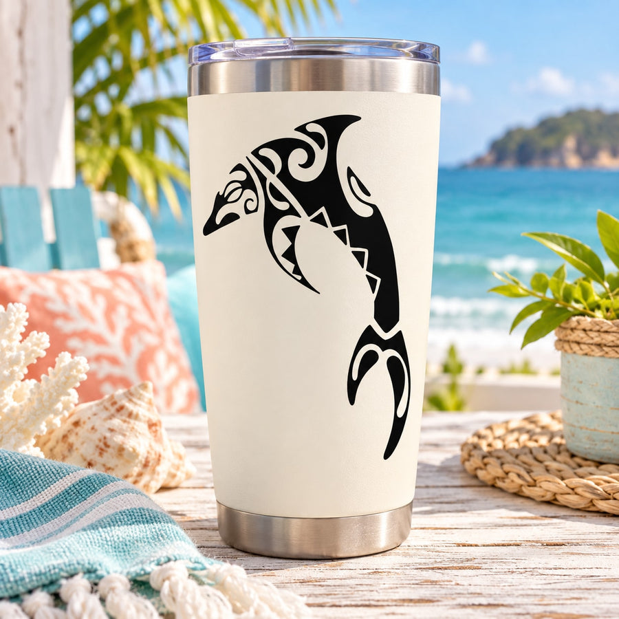 Stainless steel tumbler with black tribal dolphin decal on white surface