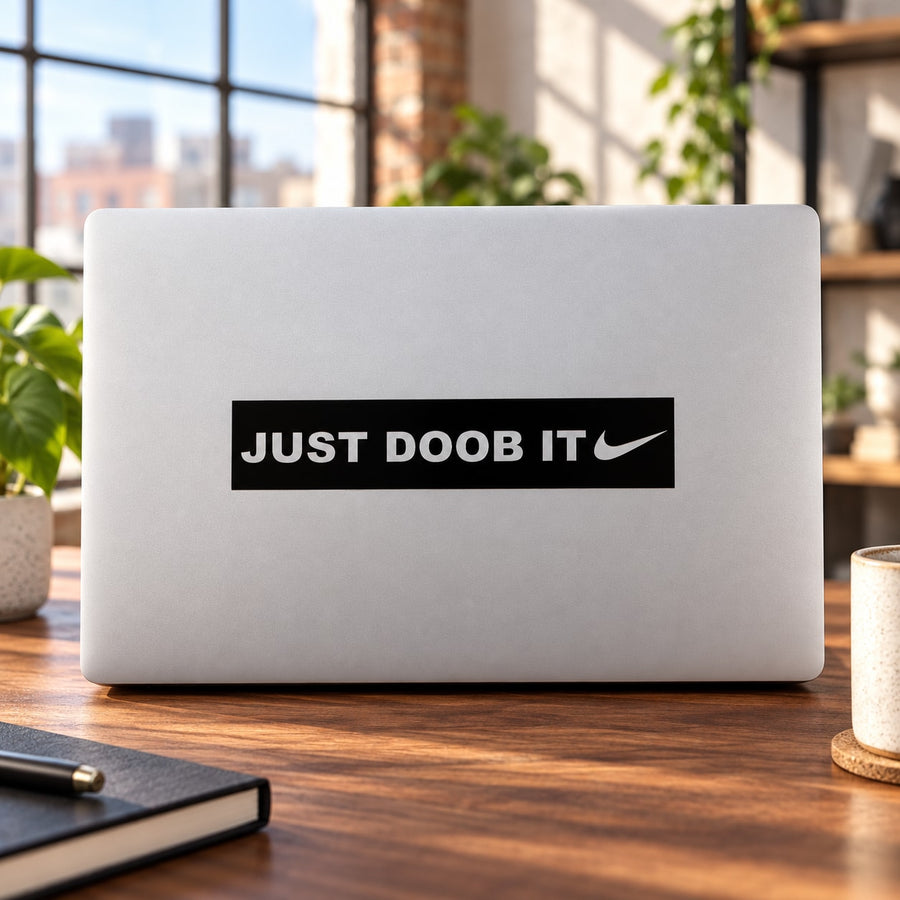 Laptop decal with black "JUST DOOB IT" text and swoosh mark, sticker centered