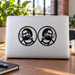 Black circular character decals on white laptop lid