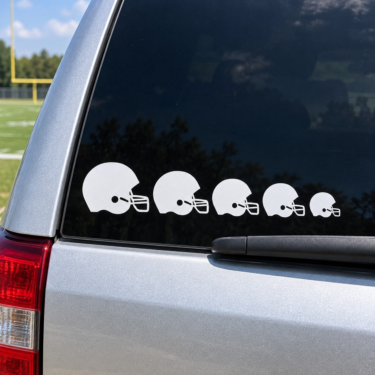 Set of white football helmet decals in a row on a dark car window