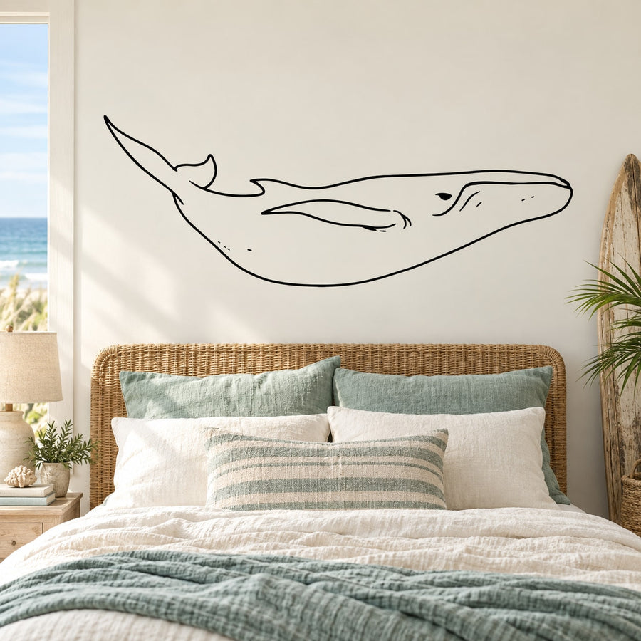 Black line-art whale wall decal with long body and tail above the bed