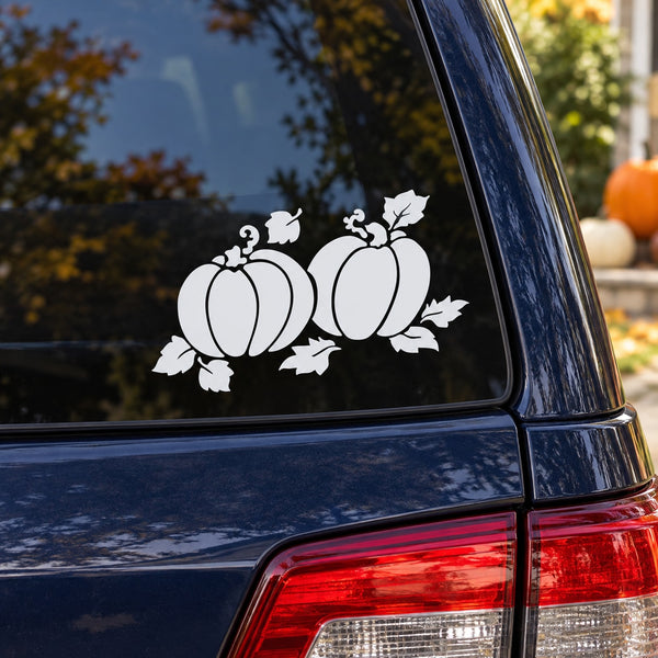 Set of two white pumpkin decals with leaves and vines on a car window