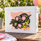 Floral holiday sticker with pink flowers, green leaves, and multicolor confetti accents