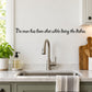 Wall decal with black cursive quote: 'No man has been shot while doing the dishes'.