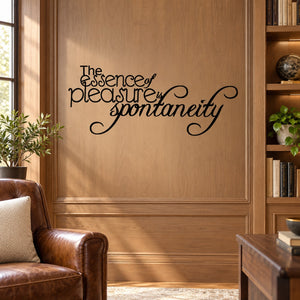 Black cursive wall decal reading “The essence of pleasure is spontaneity”.
