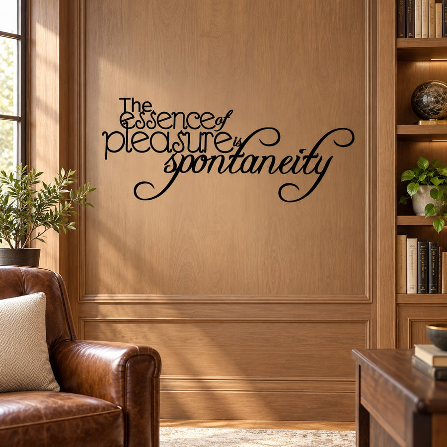 Black cursive wall decal reading “The essence of pleasure is spontaneity”.