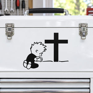 Praying Calvin decal with black cross on white surface