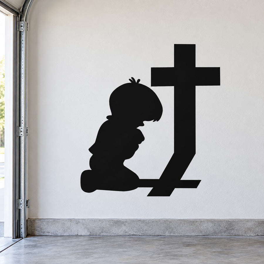 Black silhouette decal of kneeling praying boy beside a large cross