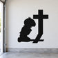 Black silhouette decal of kneeling praying boy beside a large cross