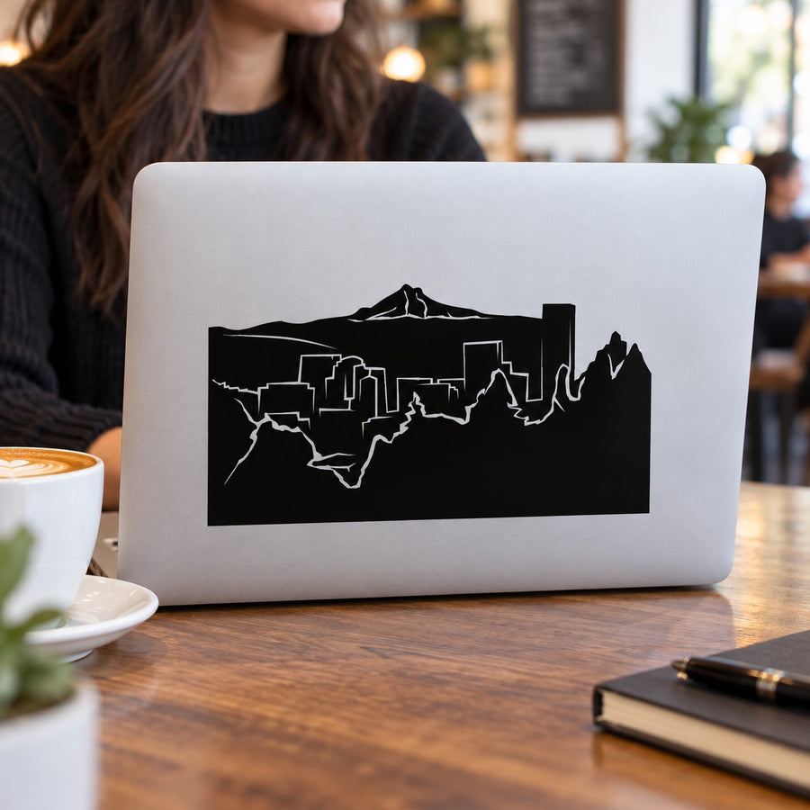 Black city skyline and volcano decal on a laptop screen