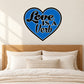 Blue heart-shaped sticker with white “Love is a Verb” lettering