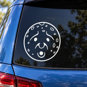 Round white moon face decal with surprised expression on car window