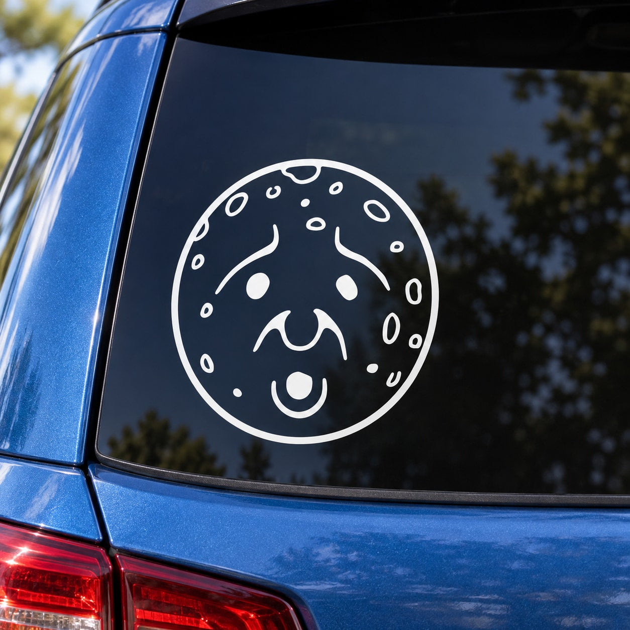 Round white moon face decal with surprised expression on car window