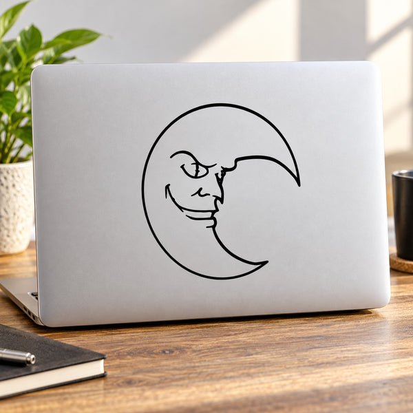 Black demon face moon decal with horns and grin, centered on a light surface