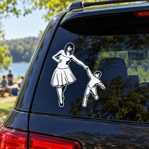 Car window decal of mother and son holding hands, white silhouette on dark panel
