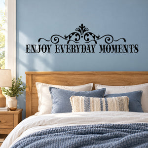 Black ornate wall decal reading 'Enjoy Everyday Moments' above bed headboard