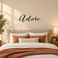 Adore wall decal with cursive black 'Adore' lettering above bed