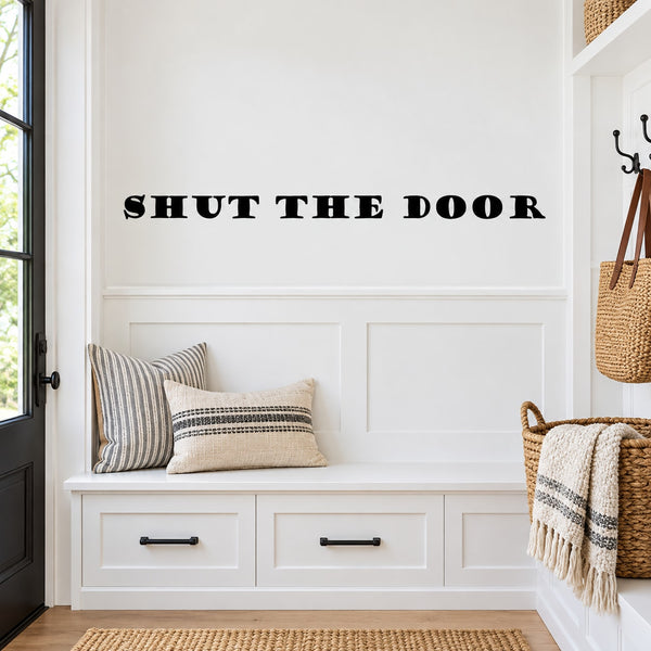 Wall decal reading "SHUT THE DOOR" in bold black letters on a light wall