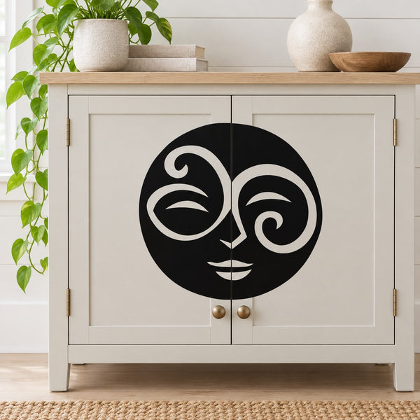 Swirl moon face decal: black circular stylized face with swirl eyes on light surface