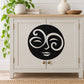 Swirl moon face decal: black circular stylized face with swirl eyes on light surface