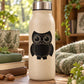 Black owl greeting decal with circular eyes on a light-colored bottle