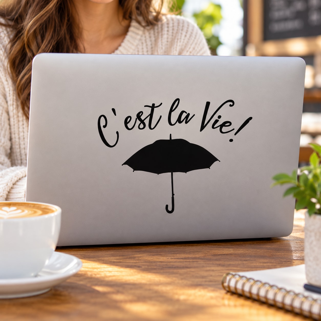 Decorative laptop decal with cursive text 'C'est la vie,' and umbrella icon