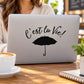 Decorative laptop decal with cursive text 'C'est la vie,' and umbrella icon