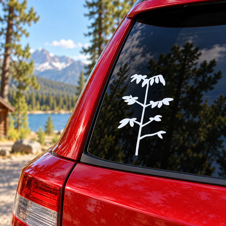 White plant sapling decal on car rear window glass, small branch and leaves.