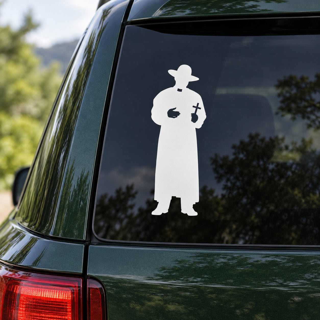 Roman Catholic priest decal with white silhouette holding a cross, on a car window