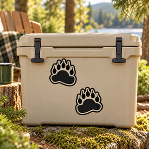 Bear paw track decal set with two black outlined paw prints on a light cooler lid