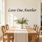 Black script wall decal reading "Love One Another"
