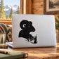 Black ram head peeking from grass decal on a white laptop
