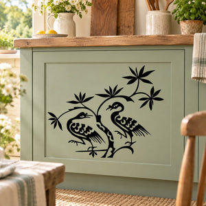 Crane pair decal with two black cranes and floral leaves on a light green cabinet door