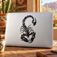 Black scorpion decal with raised claws and curved tail on a light laptop lid