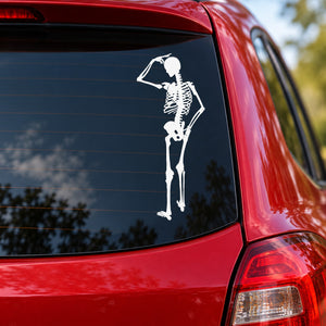 Skeleton scratching head car decal, white skull-and-skeleton design on dark window