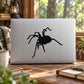 Creepy spider decal, black cartoon spider with raised legs on white surface.