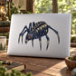 Dark spider sticker decal with orange eyes on light surface