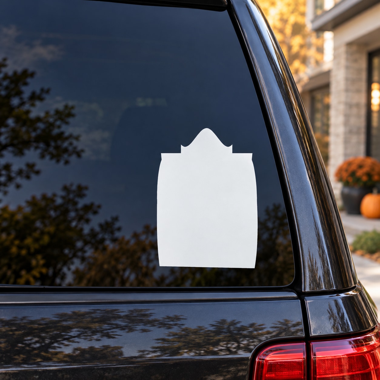 Rounded-point tombstone decal, white tombstone silhouette on car window glass.