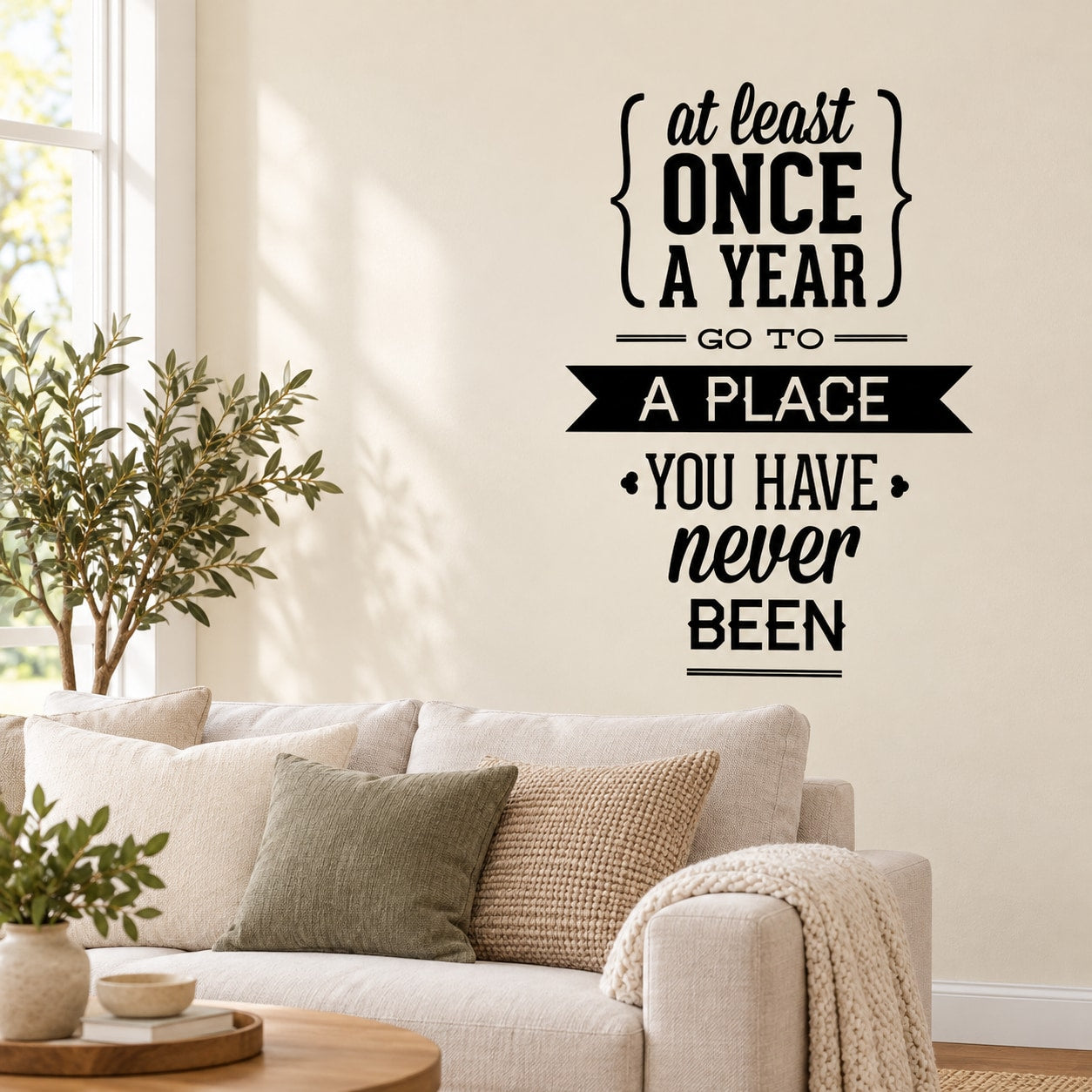 Black typography wall decal: 'At least once a year, go to a place you have never been'.