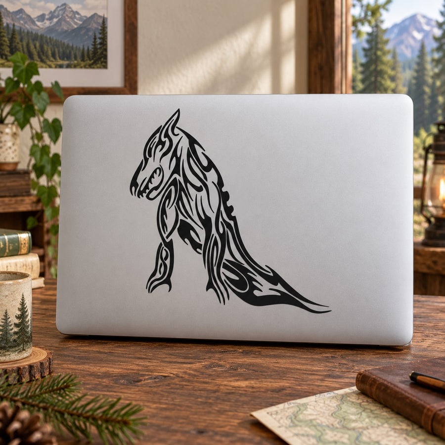 Tribal reclining wolf decal, black line art sticker on a light laptop lid