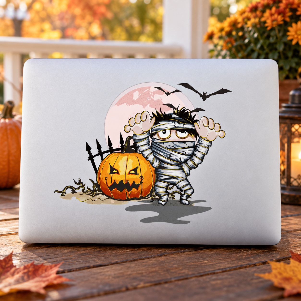 Mummy Halloween die-cut decal on a laptop lid, with jack-o'-lantern, bandages, and bats