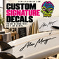 Custom signature vinyl decal on white surfboard with black cursive 'Alex Morgan'.