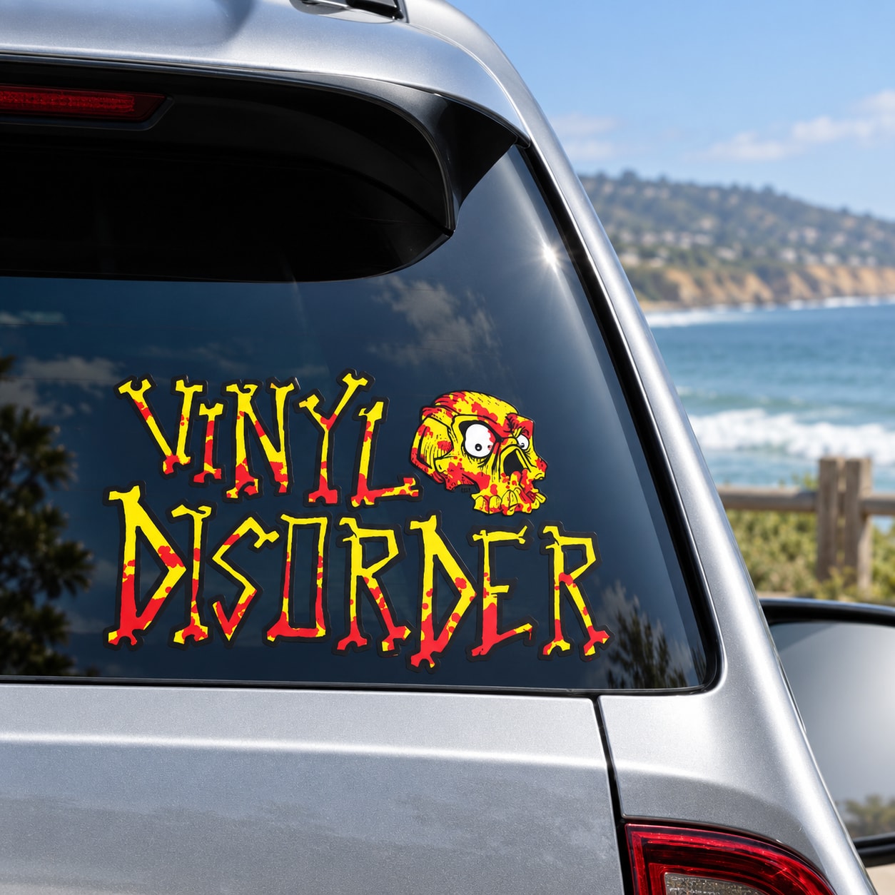 Multicolor printed die-cut vinyl lettering and skull applied directly to a vehicle window with transparent spaces between the cut shapes